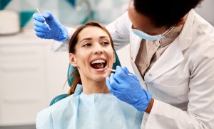 Dentist examining a patient with crowded teeth, smiling in a dental clinic setting, highlighting orthodontic care and Invisalign treatment options.